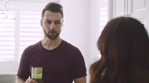 Couple enjoys green smoothies while discussing healthy living in their kitche Stock Footage 310209834