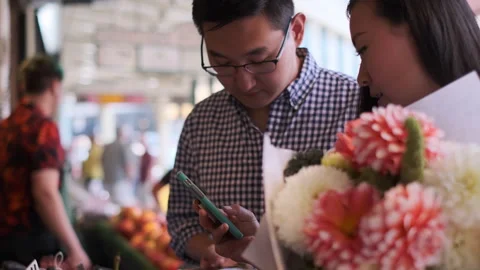 Couple enjoys market experience while learning about purchases on cellphone Stock Footage 312687102