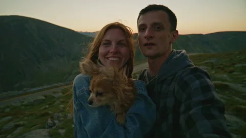 Couple enjoys time in mountains with their dog during sunset in the evening Stock Footage 345635528