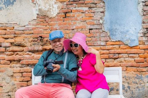Couple enjoys time together while sitting on a bench in front of a brick wa.. Stock Photos