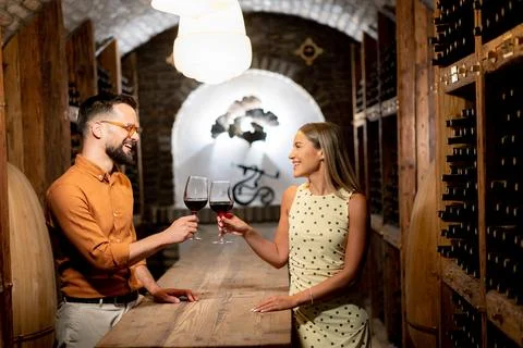 Couple enjoys wine in a cellar while celebrating a special moment together 库存照片