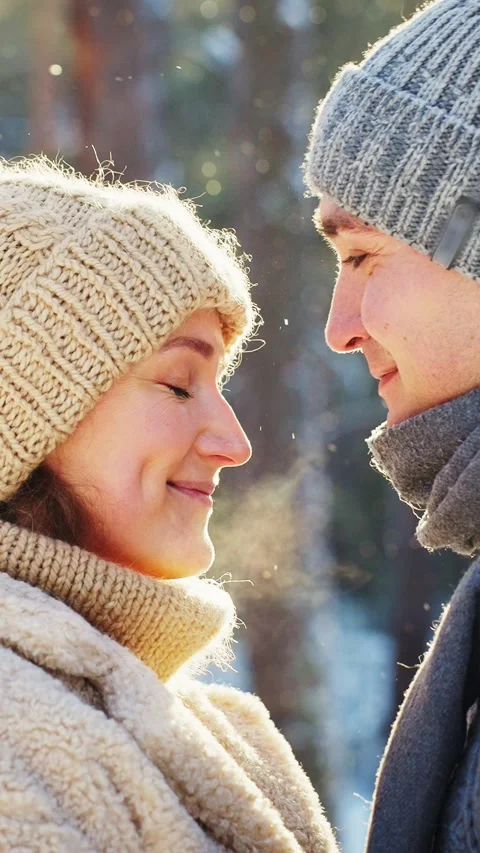 Couple enjoys a winter moment while smiling in a snowy forest Видео 296871058