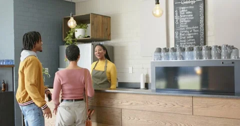 Couple entering cafe scanning menu, pointing choice, barista tapping register Vidéo 342112208