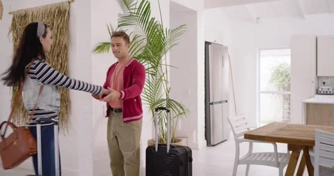Couple entering home pulling suitcase, hugging and dancing beside potted palm, Stock Footage 342608085