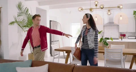 Couple entering living room pulling suitcase, hugging, sitting on sofa and Stock Footage 342608098