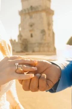Couple exchanges rings at famous tower during sunset in city square.. couple  Stock Photos