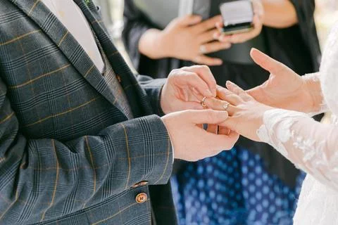 Couple exchanges wedding rings during outdoor ceremony surrounded by nature at a 스톡 사진