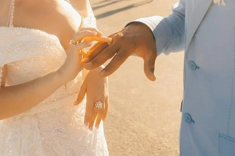 Couple exchanges wedding rings during sunset near a historic building in a ro 库存照片