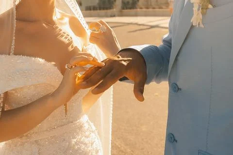 Couple exchanges wedding rings during sunset near a historic building in a ro Stock Photos