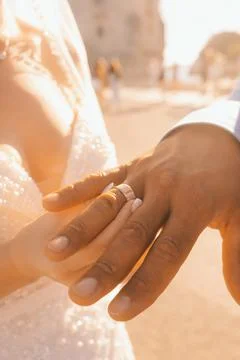 Couple exchanges wedding rings during sunset near a historic building in a ro 스톡 사진