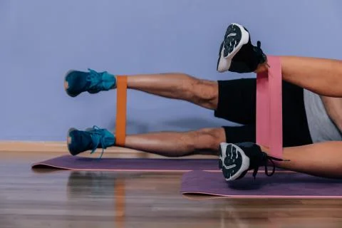 Couple exercising doing workout for legs with elastic bands lying on floor in Stock Photos