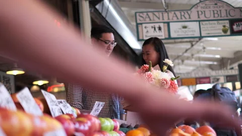 Couple explores vibrant market while enjoying flowers and fresh fruits Stock Footage 312689190