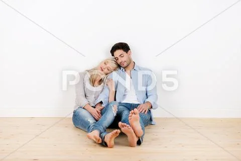 Couple with eyes closed relaxing on hardwood floor Stock Photos