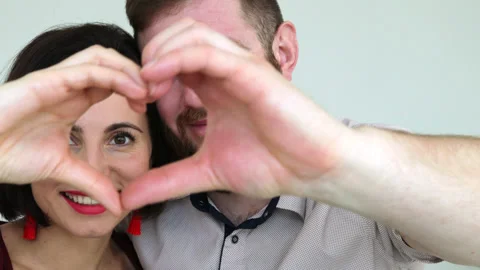 Couple faces look through joined fingers making heart shape Stock Footage 180405696