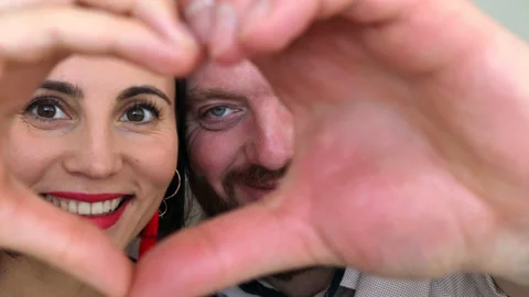 Couple faces look through joined fingers making heart shape Stock Footage 180405755
