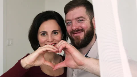 Couple faces look through joined fingers making heart Stock Footage 180406687