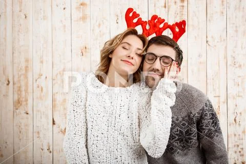 Couple in fake deer horns smiling over wooden background Stock Photos