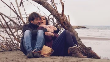 Couple feeling cold hugging in winter on the beach at sunset retro style Stock Footage 85955184