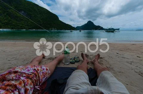Couple Feet Laying At The Beach With Calm Blue Ocean Water And Island Under