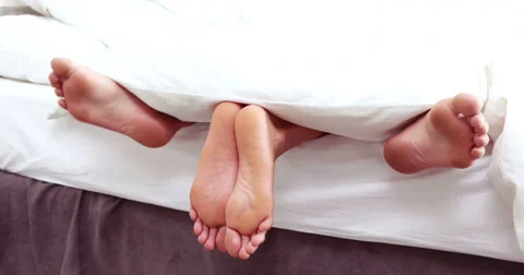Couple feet sticking out from under duvet Stock Footage 59790300