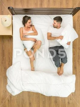 The couple fight pillows on the bed. View from above Stock Photos