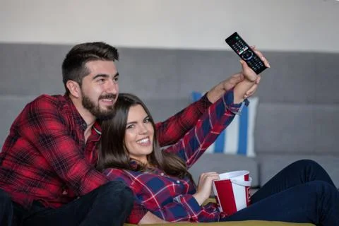 Couple fighting for remote control while watching TV at home Foto stock