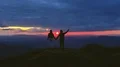 The couple with a firework stick standing on a mountain on a sunset background 4k or 4k+ Resolution