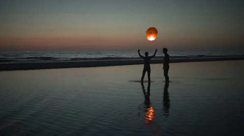 Couple flys a floating asian lantern at the ocean Stock Footage 40816361