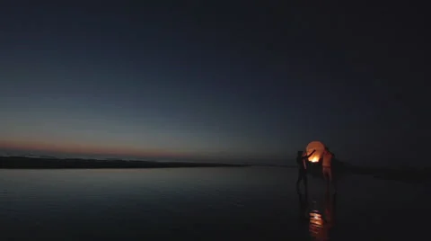 Couple flys a floating asian lantern at the ocean 2 - static shot Stock Footage 40903493