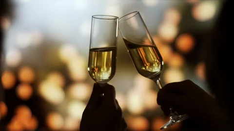 Couple on a foreground clinks with Two glasses of champagne over Holiday Bokeh Vidéo 121248201