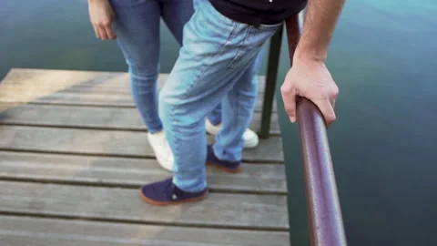 Couple framed by a walkway pole by the river as the water slowly flows by Video stock 280121616