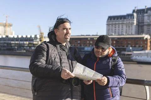 Couple of friends consulting the map while exploring Puerto Madero Buenos Aires Fotos Stock