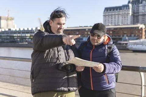 Couple of friends consulting the map while exploring Puerto Madero Buenos Aires Fotos Stock