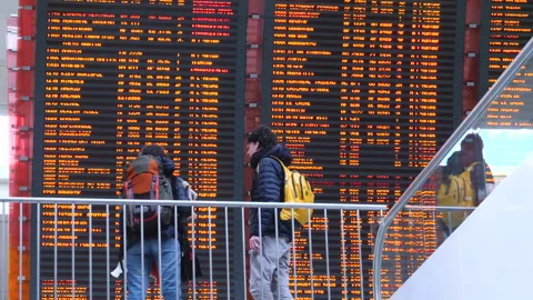 Couple in front of real flight schedule as seen in busy CDG Parisian airport Stock Footage 166179608