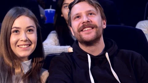 Couple gazes lovingly at each other in a cozy movie theater Stock Footage 311894499