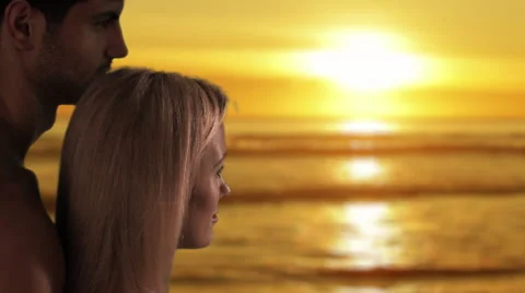 Couple gazing at sun setting over the ocean. Stock Footage 43680167