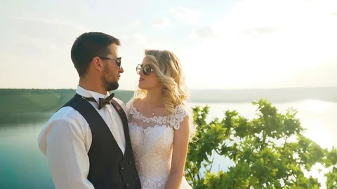 Couple gently embrace standing on the edge of the cliff and looking on the lake Stock Footage 107807255