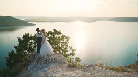 Couple gently embrace standing on the edge of the cliff and looking on the lake Stock Footage 107807341