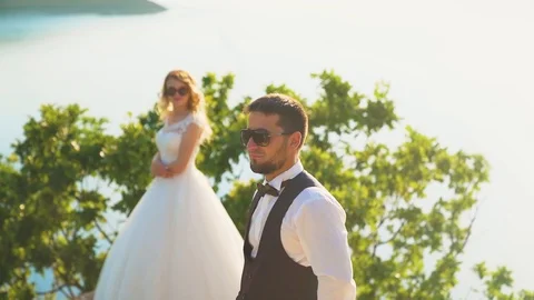Couple gently embrace standing on the edge of the cliff and looking on the lake Stock Footage 107807833