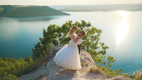 Couple gently embrace standing on the edge of the cliff and looking on the lake Stock Footage 107807936