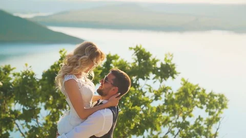 Couple gently embrace standing on the edge of the cliff and looking on the lake Stock Footage 107808094