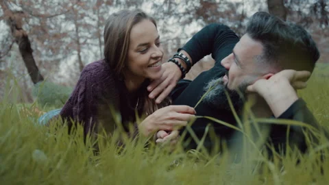 Couple gently touching each other's hair while lying outside on grass Stock Footage 275279853