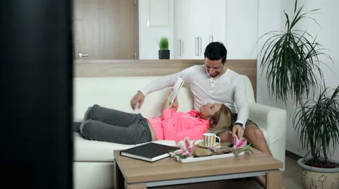 Couple gets bored of watching TV and reading a book, and they start kissing. Stock Footage 47258514