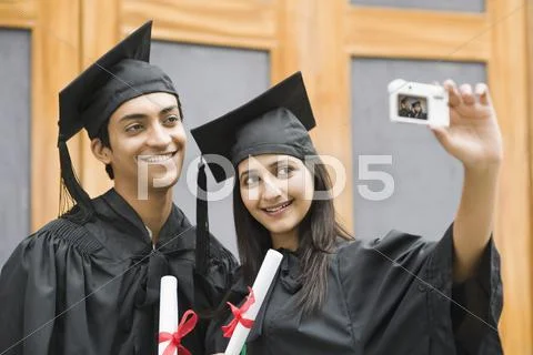 Couple in graduation gown taking a picture of themselves Stock Photos