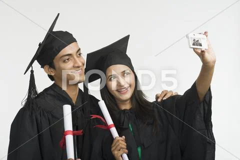 Couple in graduation gown taking a picture of themselves Stock Photos