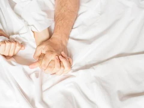 Couple hands pulling white sheets in ecstasy, orgasm. Concept of passion Stock Photos
