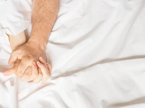 Couple hands pulling white sheets in ecstasy, orgasm. Concept of passion Fotos Stock