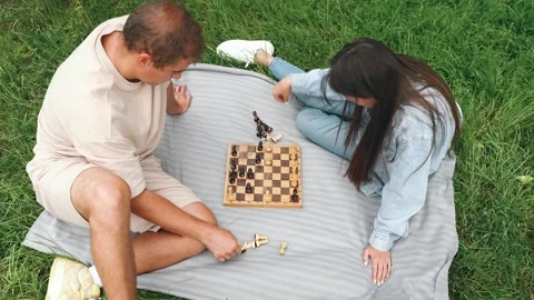 A couple is happily engaged in a friendly chess game outdoors in the lush park Stock Footage 306052697