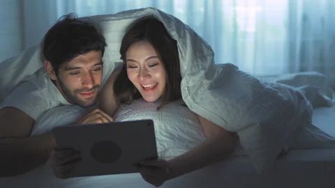 A couple is happy to look at something on the computer together in the bedroom. Stock Footage 141381985
