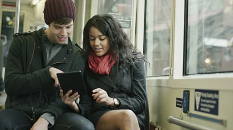 A couple has fun riding the tram as they play with their tablet Stock Footage 34017234